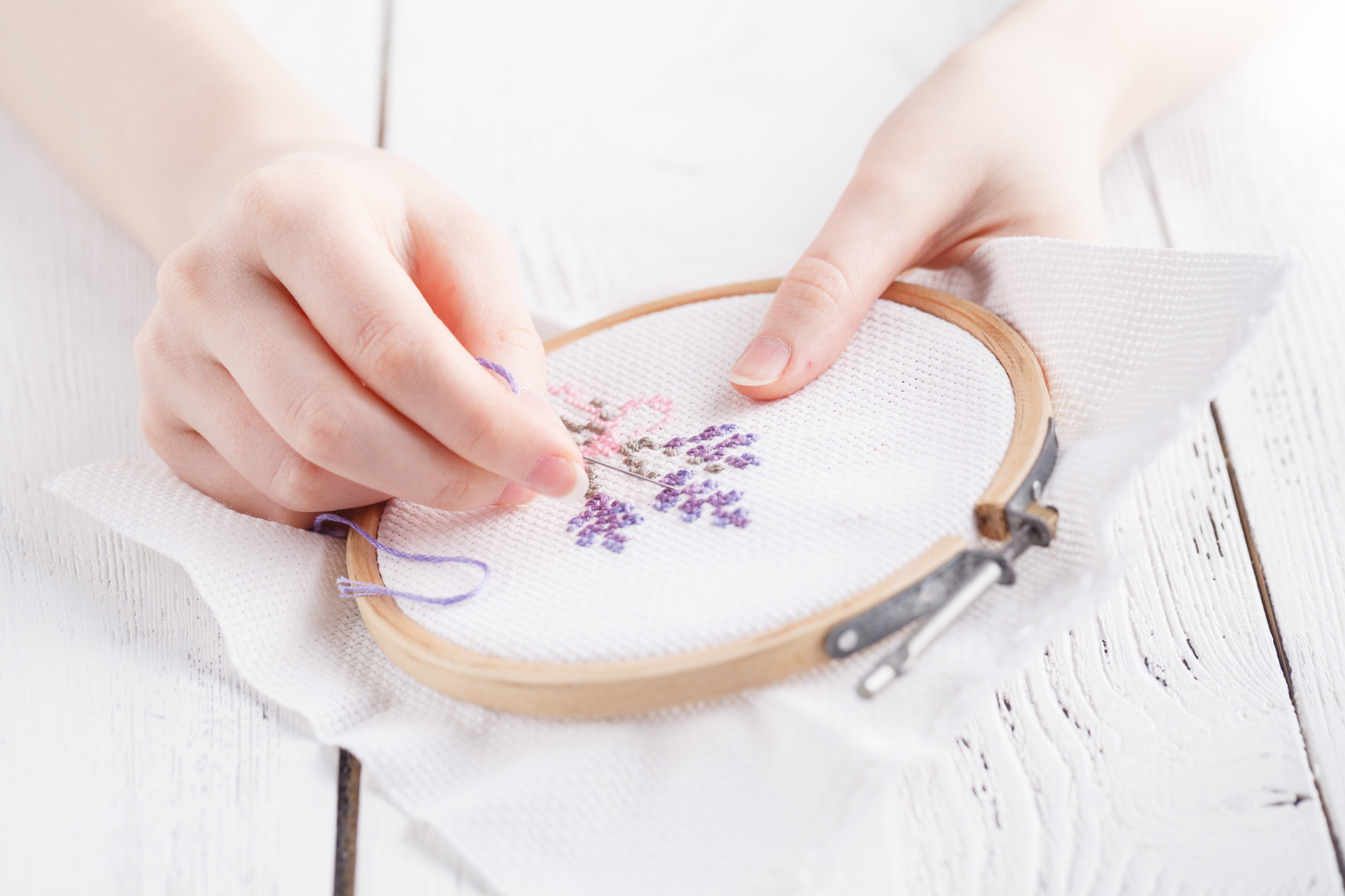 close-up of hand embroidering floral motif on linen